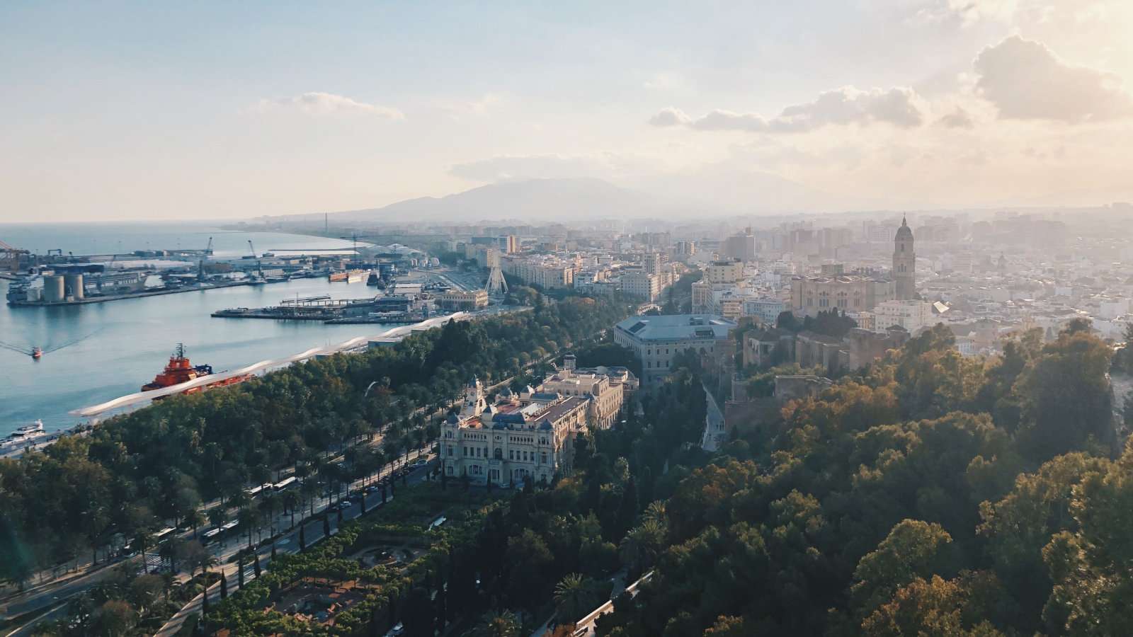 An overhead view of Malaga city and harbour with hazy clouds in the background.