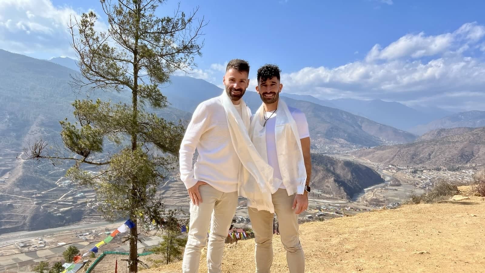 Gay couple wearing a Bhutanese khata white welcome scarf.