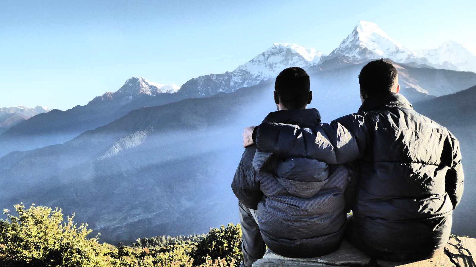 Gay couple embracing in the Himalayas during Annapurna Trek in Nepal.