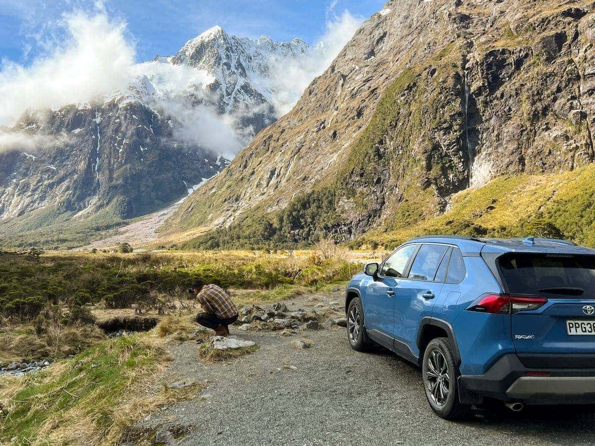 Road trip in New Zealand mountain backdrop and Stefan taking a photo.