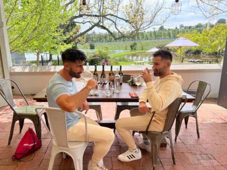 Seby and Stefan of Nomadic Boys sitting on a terrace and tasting some wine in Cape Town.